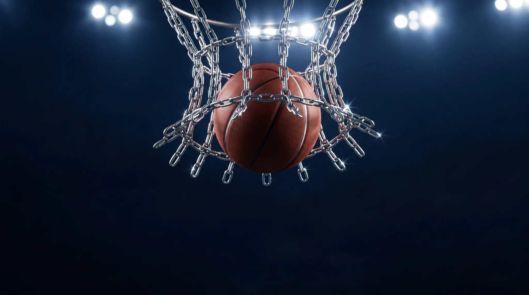 A dramatic closeup shot of a brown-orange basketball dropping through a heavy silver steel chain net on a basketball hoop. Specular highlights sparkle across the polished metal chain links as they flare outward around the ball. In the background, bright arena floodlights glow softly against a dark navy blue atmosphere, evoking the excitement of streetball or competitive basketball under stadium lights.