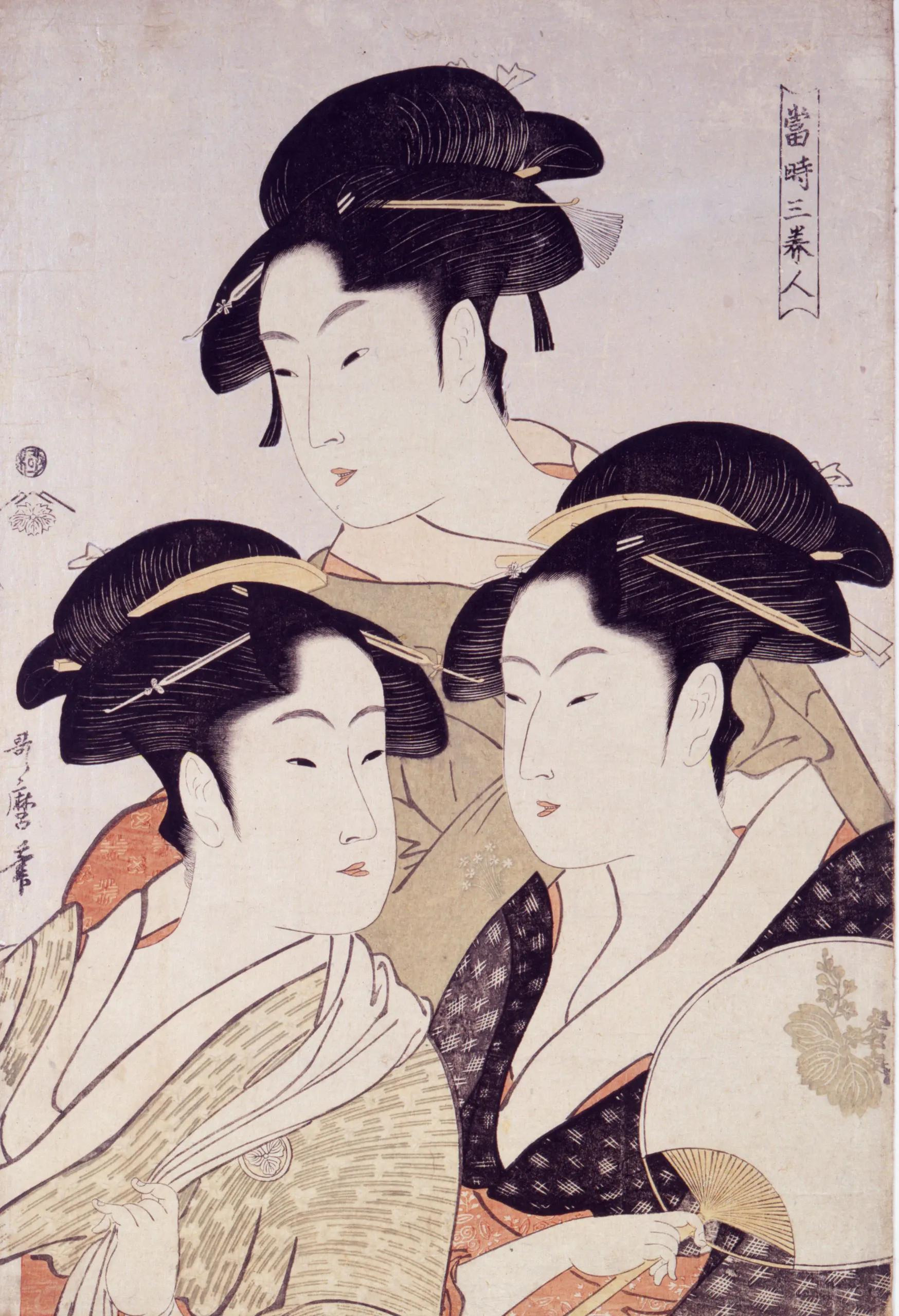 A vertically composed ukiyo-e-style color print shows three closely grouped women with elaborate black updos, pale faces, and layered kimono-like robes. The upper woman is centered behind two women in front; the lower-right woman holds an open folding fan. Decorative hair ornaments, patterned fabrics, and Japanese calligraphic marks appear around the figures.