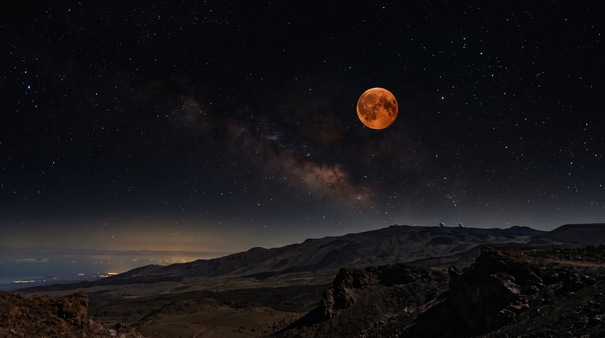 A night landscape showing an orange-red full moon glowing in a starry night sky alongside the Milky Way galactic core, suspended over a dark volcanic mountain range with distant astronomical observatories on the ridge line.